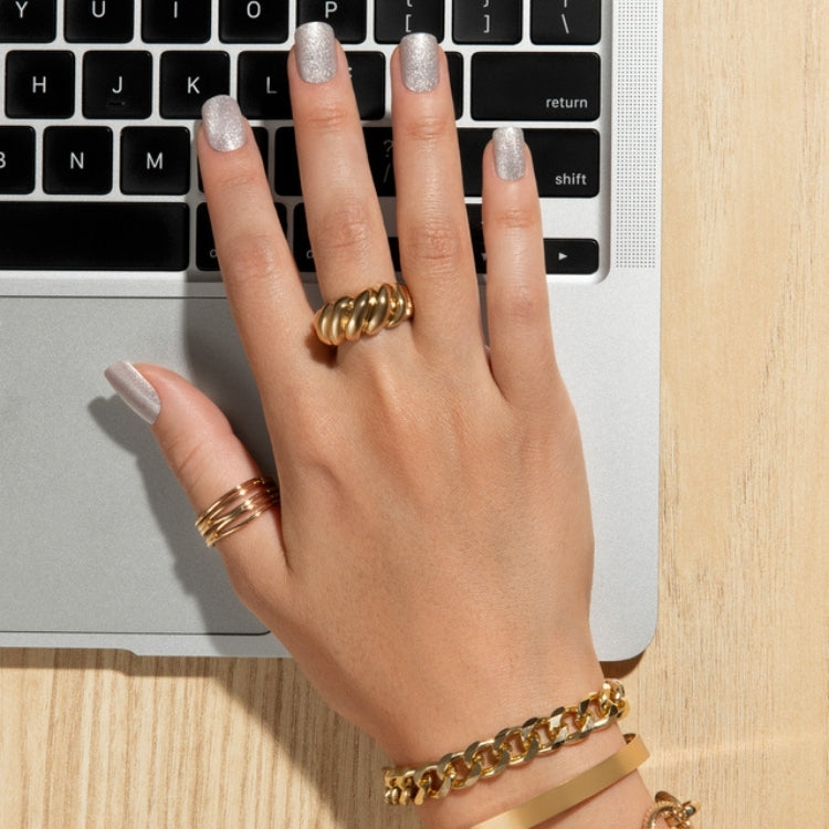 Gel Fantasy Magnetic - Dignity in een glanzende, neutrale kleur op een hand met gouden sieraden, naast een laptop.