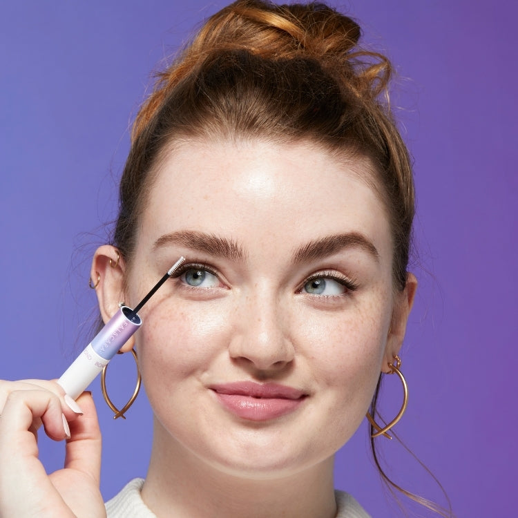 Falscara WISPS Multi - Bambi, een vrouw die de applicator vasthoudt, met een paarse achtergrond en natuurlijke make-up.