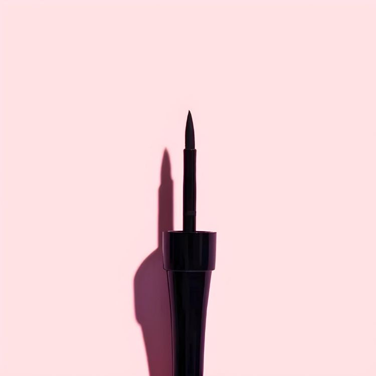 Fast Stroke Liquid Eyeliner Black in een slanke zwarte verpakking met een fijne applicatorpunt op een roze achtergrond.